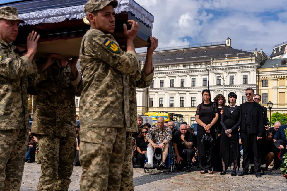 A pregnant soldier mourns her 21-year-old husband at his funeral in Ukraine
