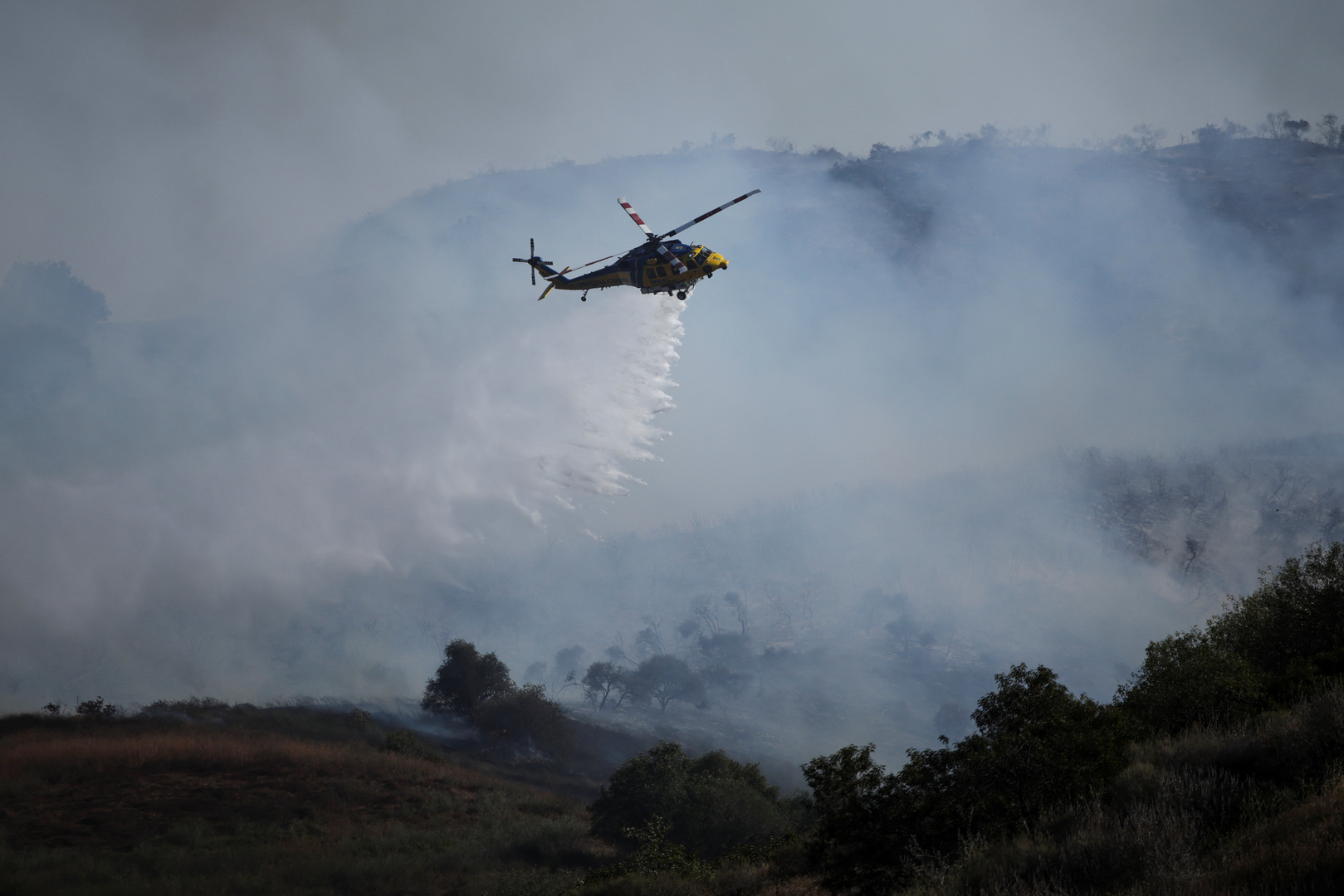 Helicopters douse flames threatening hillside homes in California